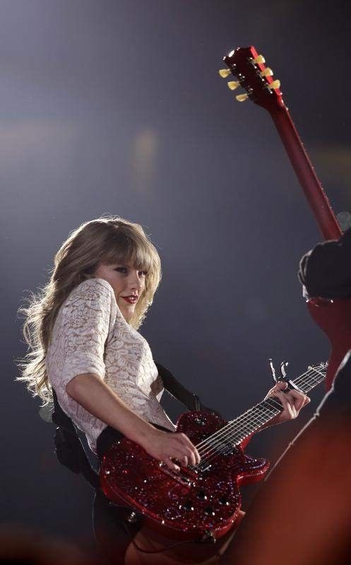a woman holding a red guitar in her right hand