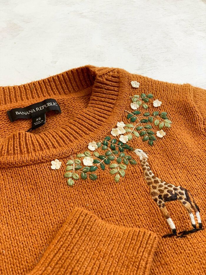 an orange sweater with a giraffe painted on it