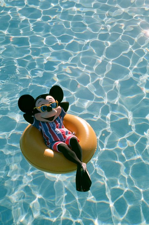 a mickey mouse floating on top of an inflatable floatie pool raft near the water