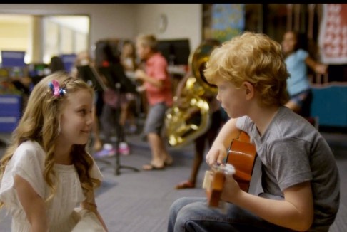 two young children are playing instruments in a classroom