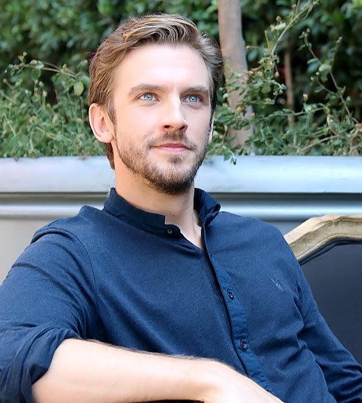 a man sitting in a chair with his arms crossed and looking at the camera while wearing a blue shirt