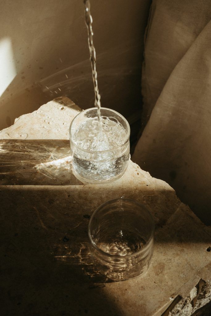 a glass filled with water sitting on top of a table next to a metal chain