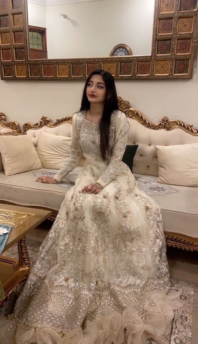 a woman sitting on top of a couch in a white dress