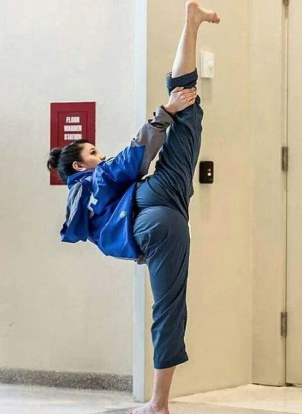 a woman doing a handstand on the floor in front of a door with her legs up