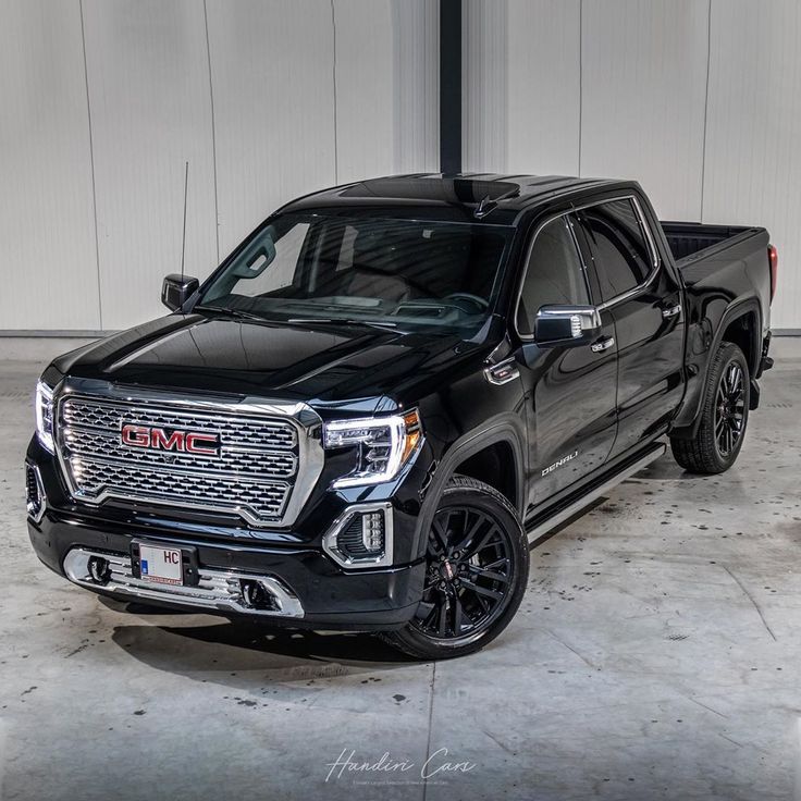 a black truck parked in a garage next to a white and gray wall with the words gmc on it