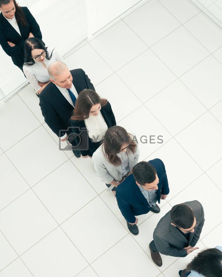 group of business people standing in a row looking down at their cell phones, from above