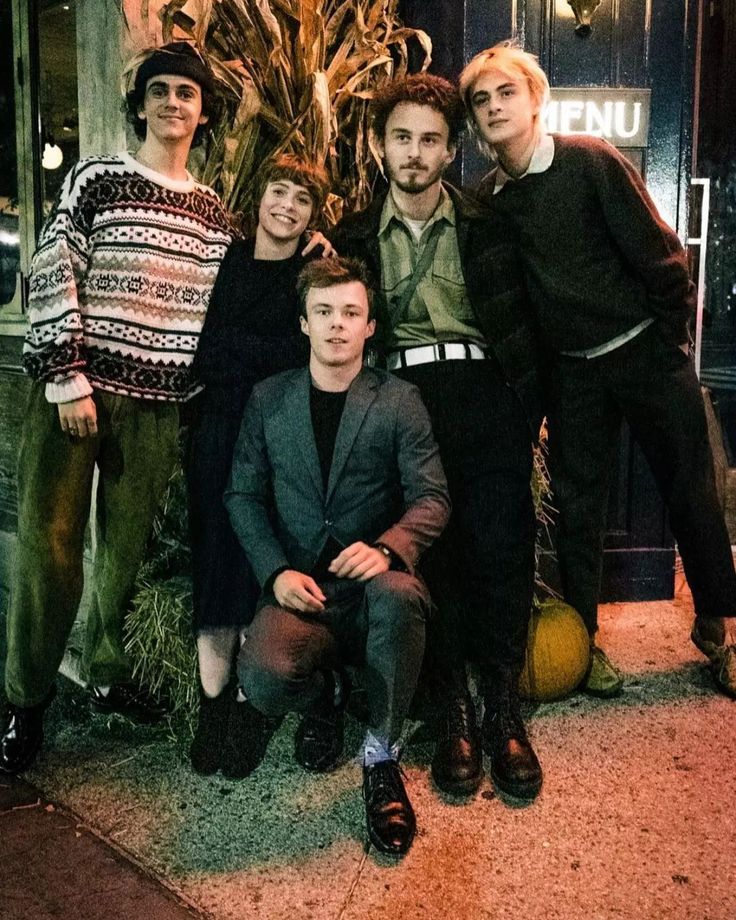 a group of people standing next to each other in front of a building at night