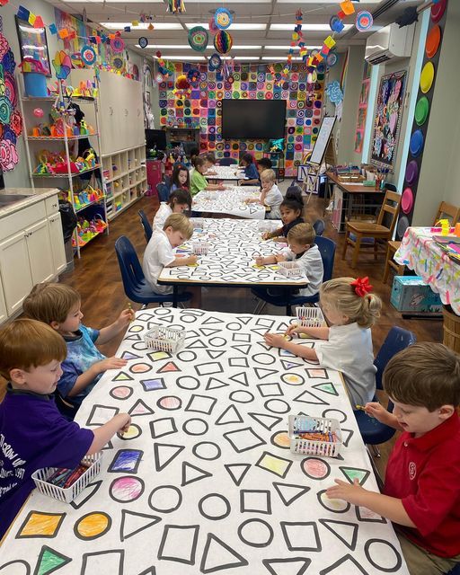 a group of children sitting around a table with paper decorations on it