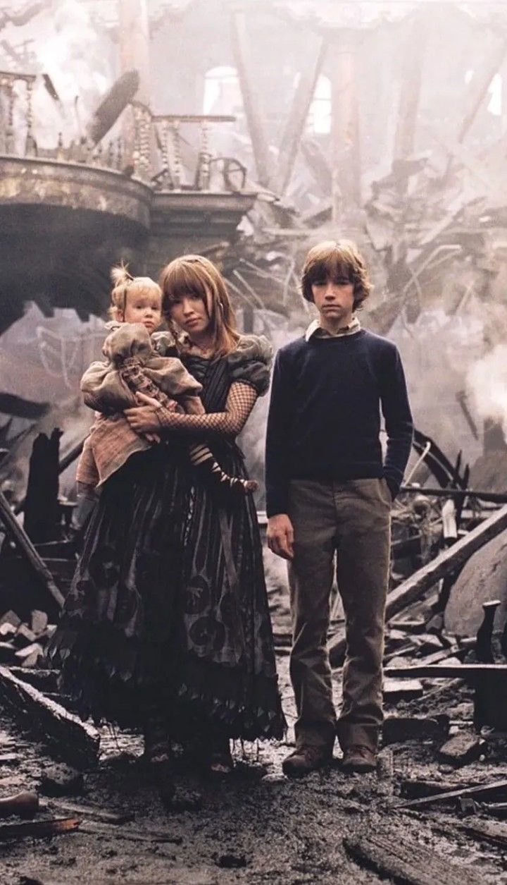 two people and a child standing in front of a destroyed building with debris on the ground
