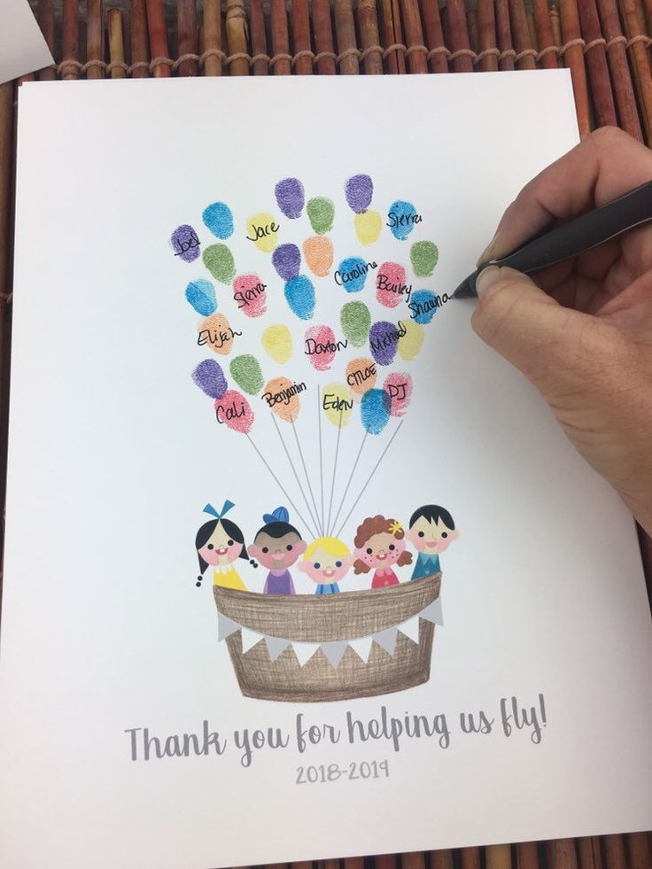 a hand holding a pen writing on a card with balloons in the shape of people