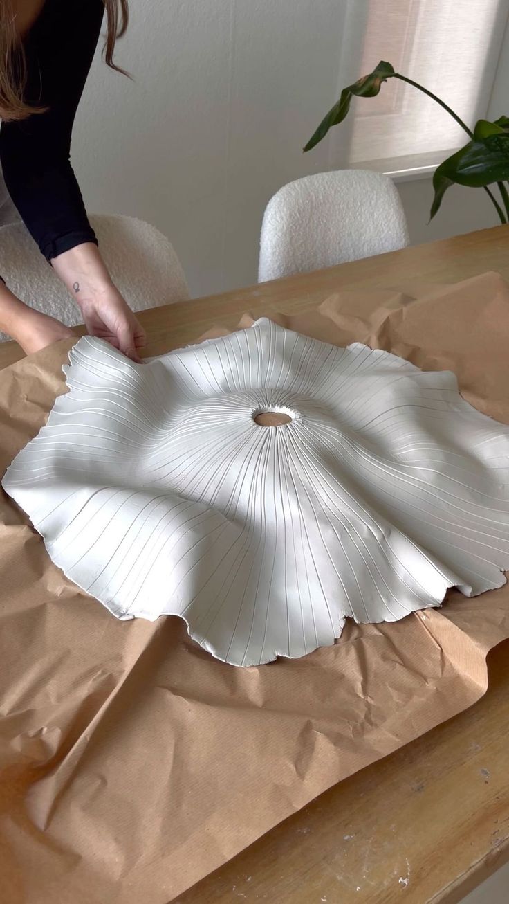 a woman is making a paper flower decoration