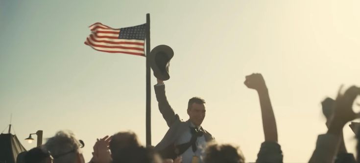 a man raising his arms in the air with an american flag on top of him