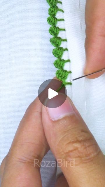 someone is stitching the end of a green piece of fabric