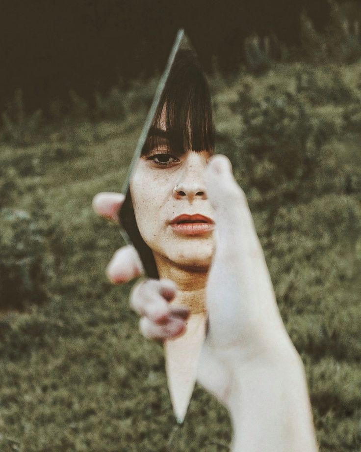 a woman holding a pair of scissors up to her face while standing in the grass