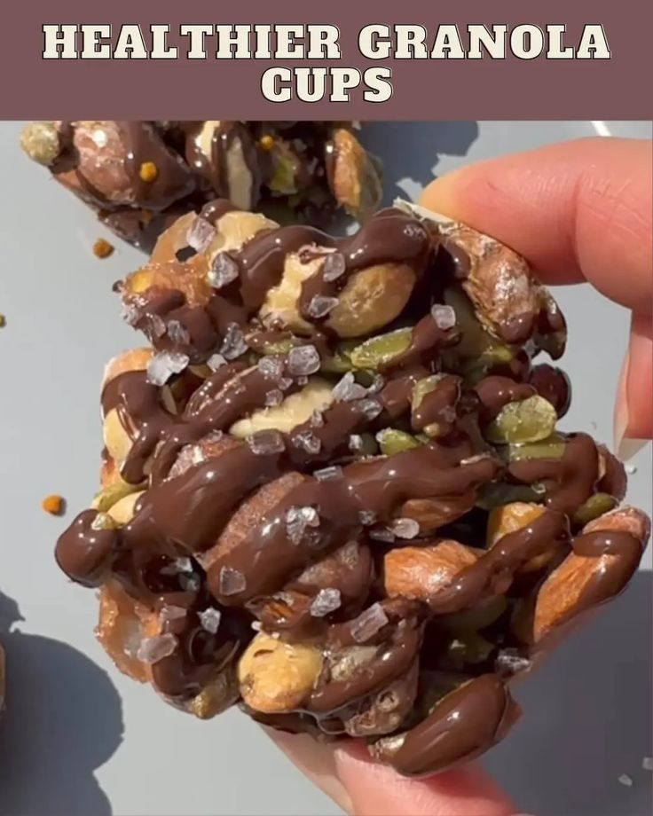 someone holding up some kind of granola with nuts on it and the words healthier granola cups above them