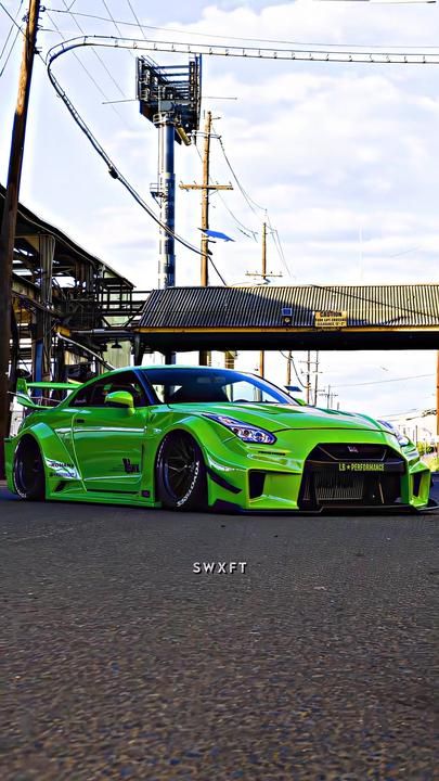 a green sports car parked in front of a building with an overpass above it