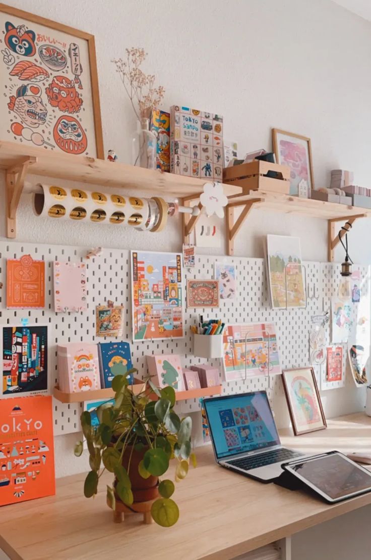 there is a desk with many pictures on the wall and a potted plant next to it