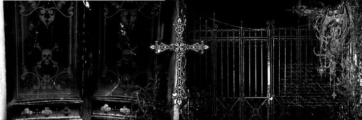 a black and white photo of an iron gate with a cross at the top in front of it