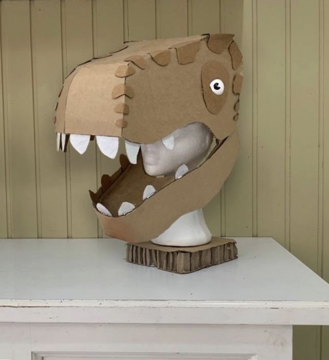 a cardboard dinosaur head sitting on top of a white table