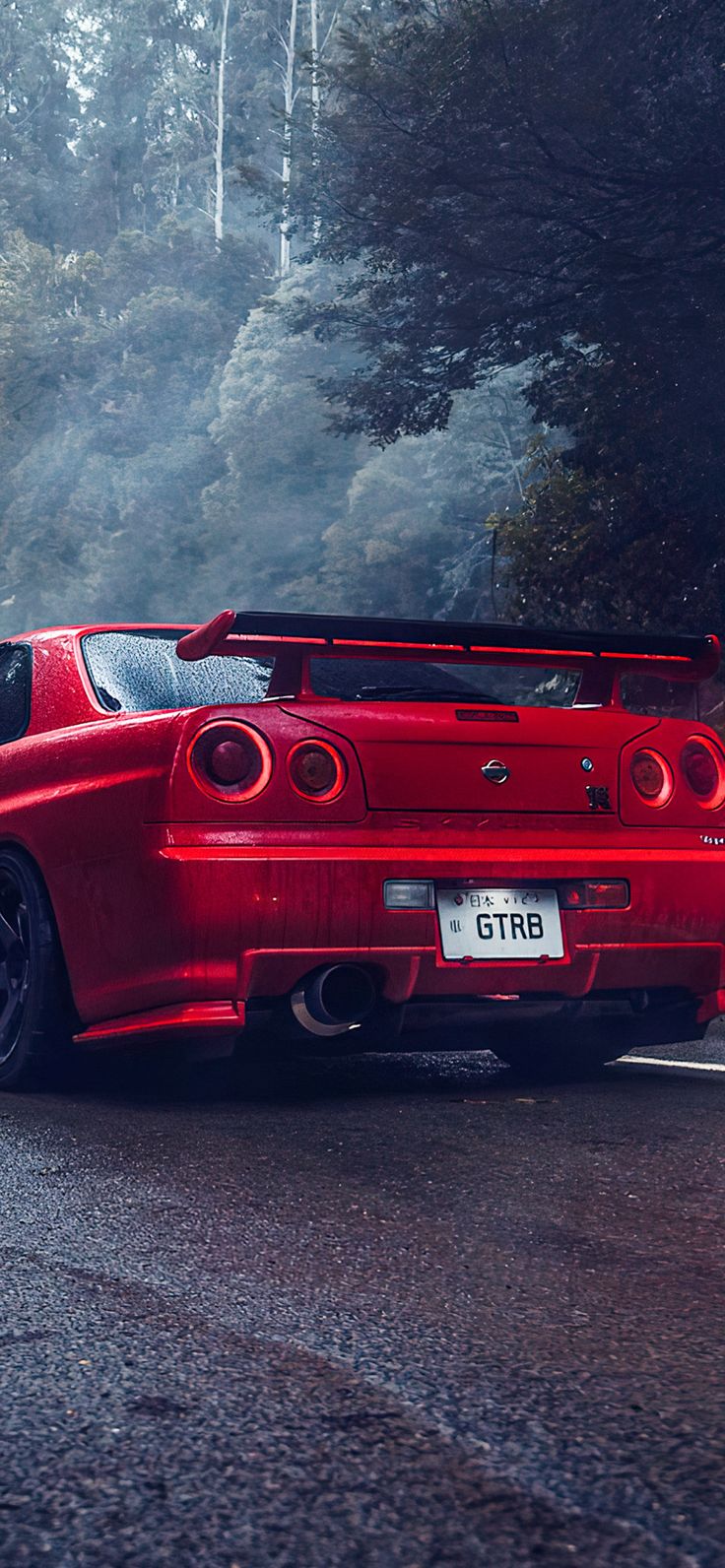 a red sports car is parked on the side of the road in front of some trees