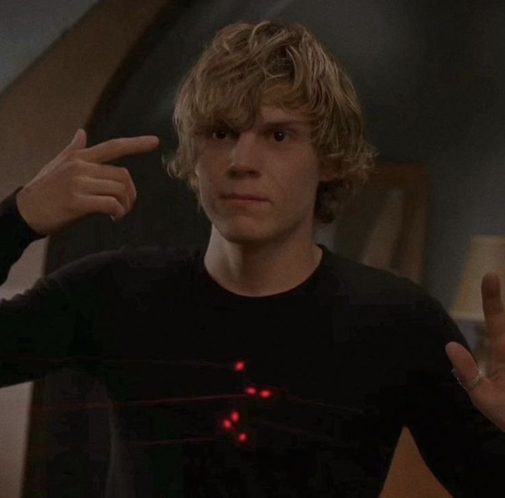 the young man is pointing at something with his fingers in front of him and wearing a black t - shirt