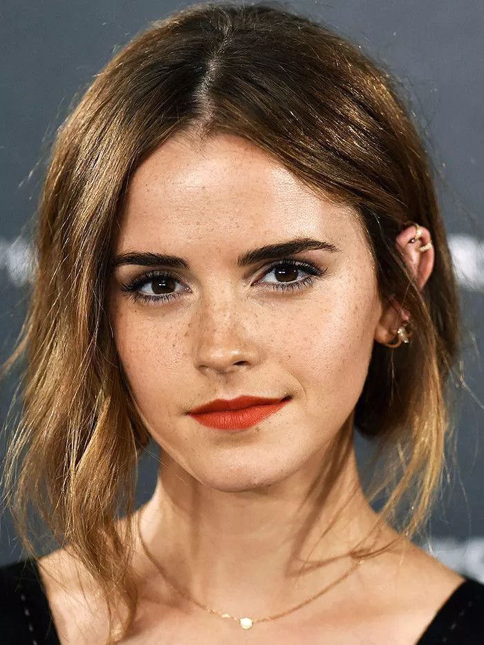 a close up of a woman with brown hair and orange lipstick on her face, wearing a black dress