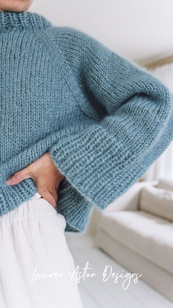 a woman wearing a blue sweater with her hands on her hips and the back of her body