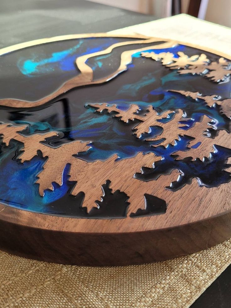 a wooden cutting board with blue and black designs on the top, sitting on a table