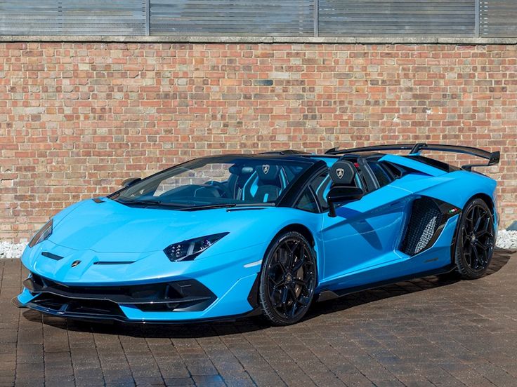 a blue sports car parked in front of a brick wall