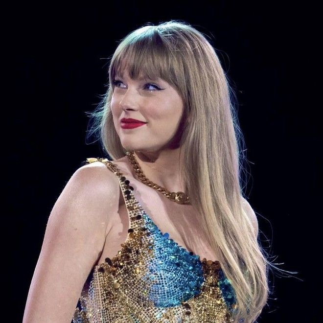 taylor swift wearing a blue dress with gold sequins and red lipstick on stage