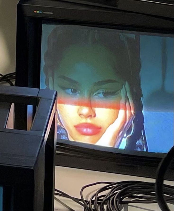 a television screen with a woman's face on it and wires in front of it