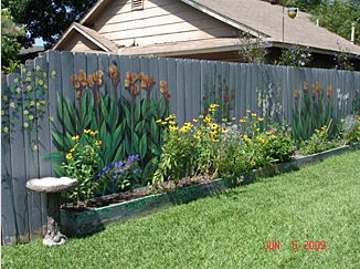 a fence with flowers painted on it in front of a house