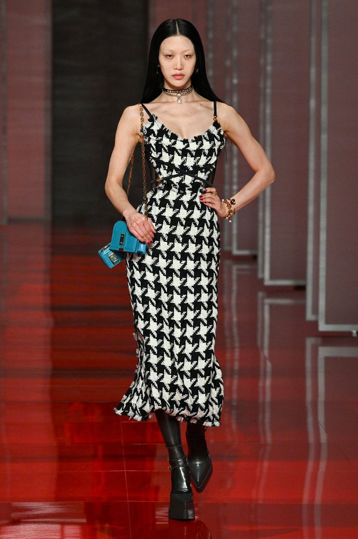 a model walks down the runway in a black and white dress with hounds on it