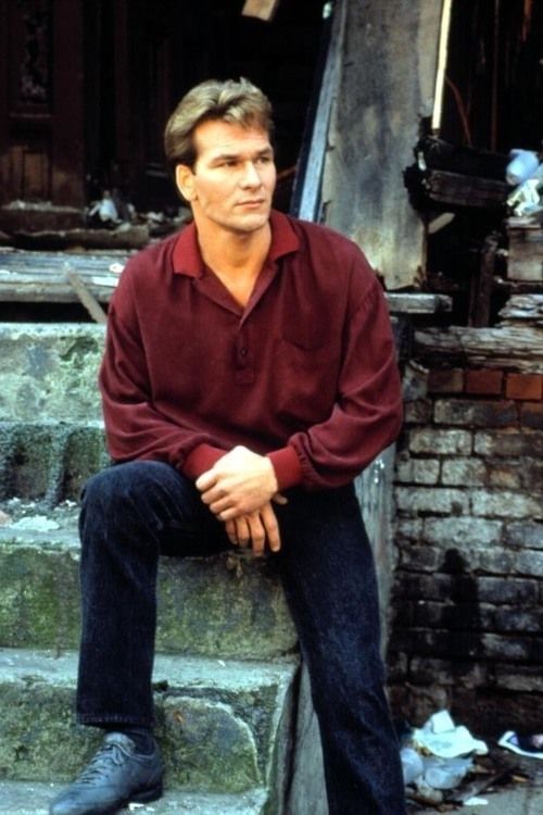 a man sitting on the steps in front of a building wearing a red shirt and blue jeans