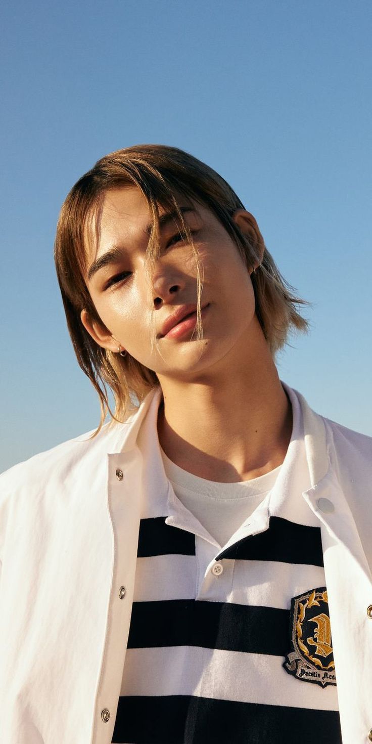 a young man with long hair wearing a white jacket and black and white striped shirt