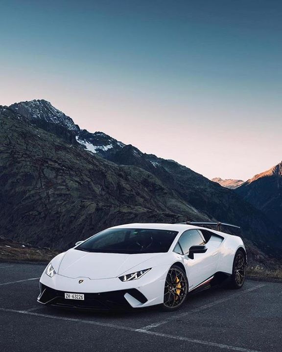 a white sports car parked in front of mountains