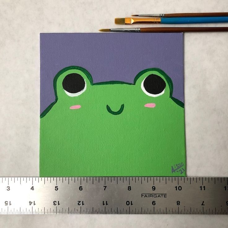 a piece of paper with a green frog on it next to a ruler and pencils