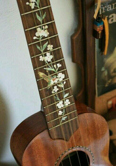 an ukulele with flowers painted on the fret and strings is sitting in front of a wall