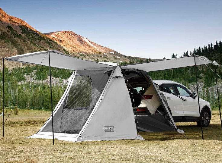 a car is parked in front of a tent with the door open and it's interior opened