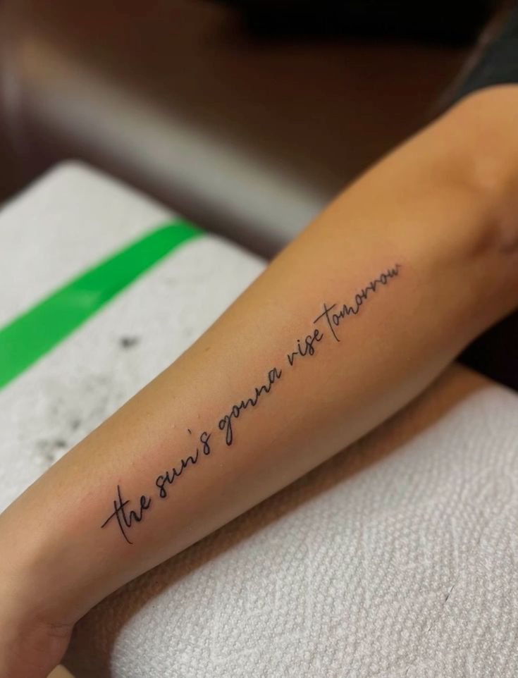 a woman with a tattoo on her arm that says the story is never told in cursive writing