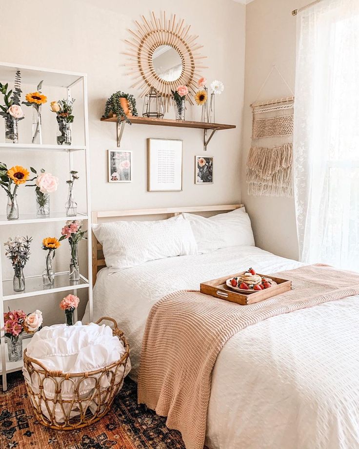 a white bed sitting in a bedroom next to a wooden table with flowers on it