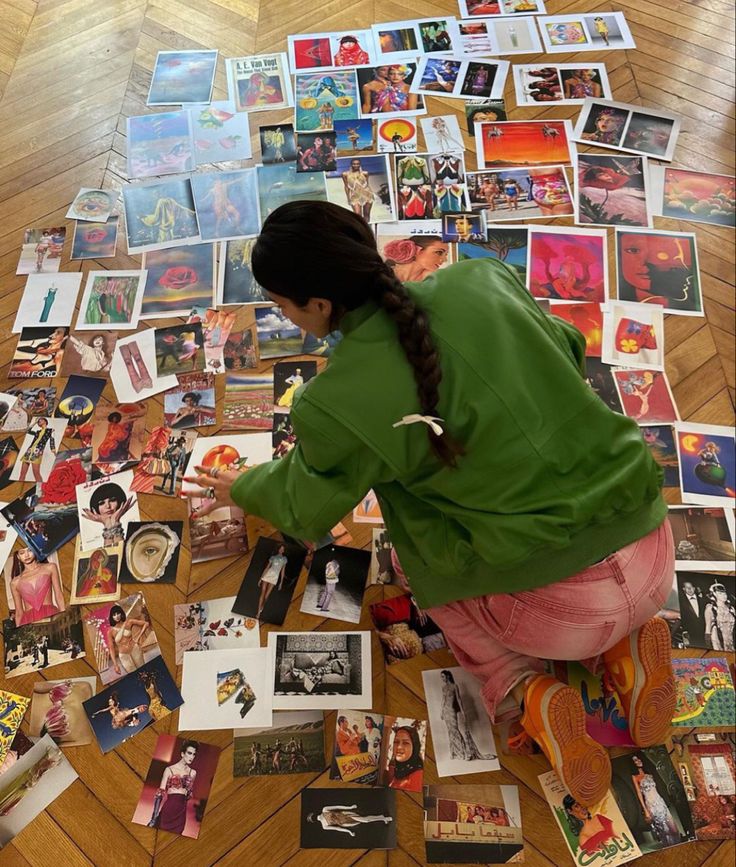 a woman sitting on the floor surrounded by pictures