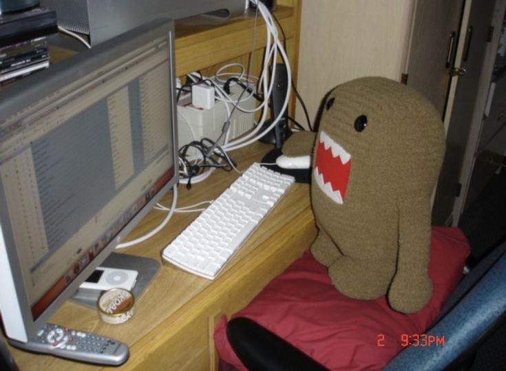 a stuffed animal sitting in front of a computer monitor on a desk next to a keyboard and mouse
