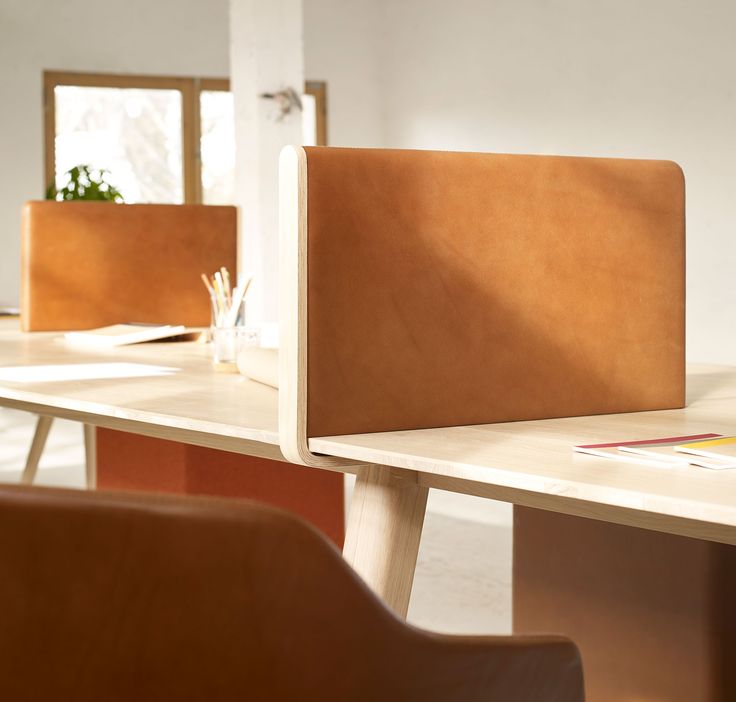 a laptop computer sitting on top of a wooden table next to a brown leather chair