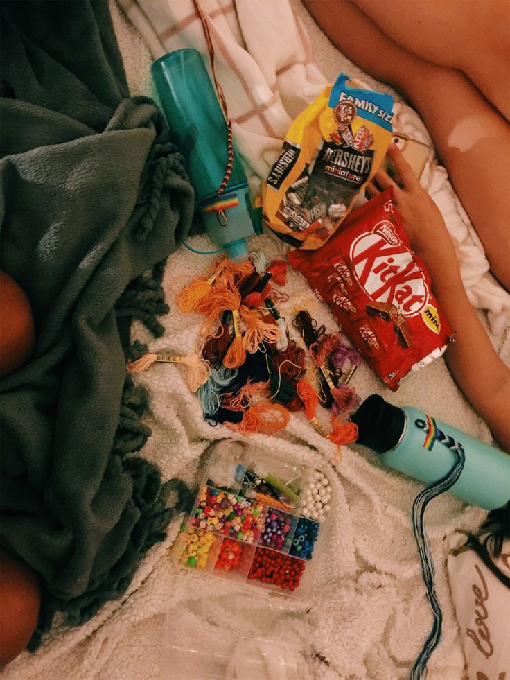 a person laying on top of a bed next to candy