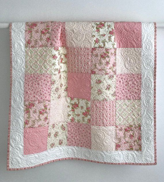 a pink and white quilt hanging on the wall