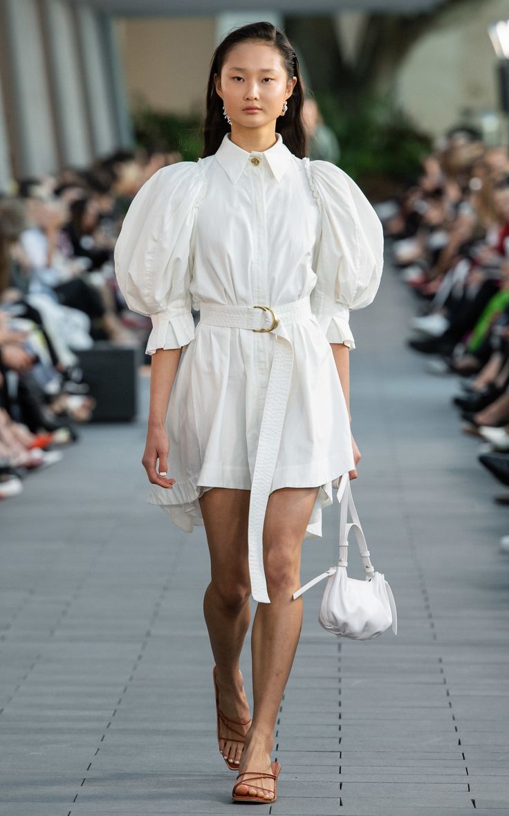 a model walks down the runway in a white dress with puffy sleeves and high heels