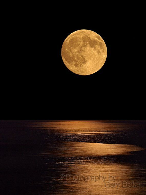 the full moon is reflected in the water and it looks like it has just been taken off