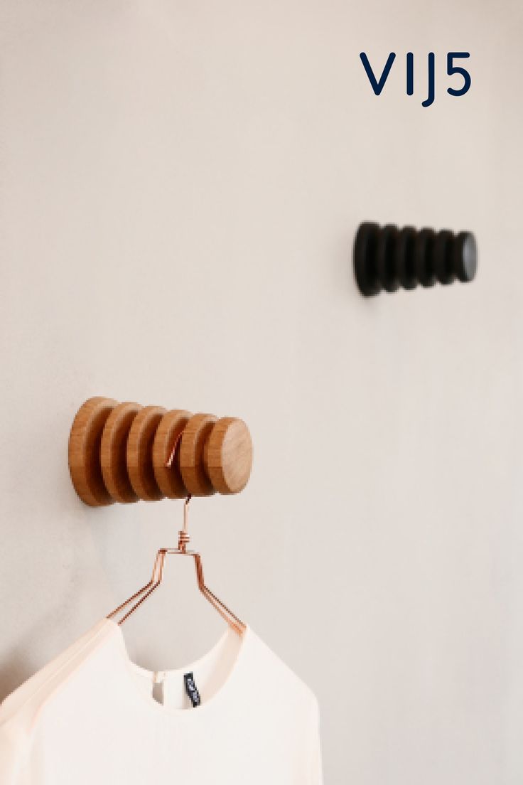 a white t - shirt hanging on a wall next to a pair of black and brown hair pins