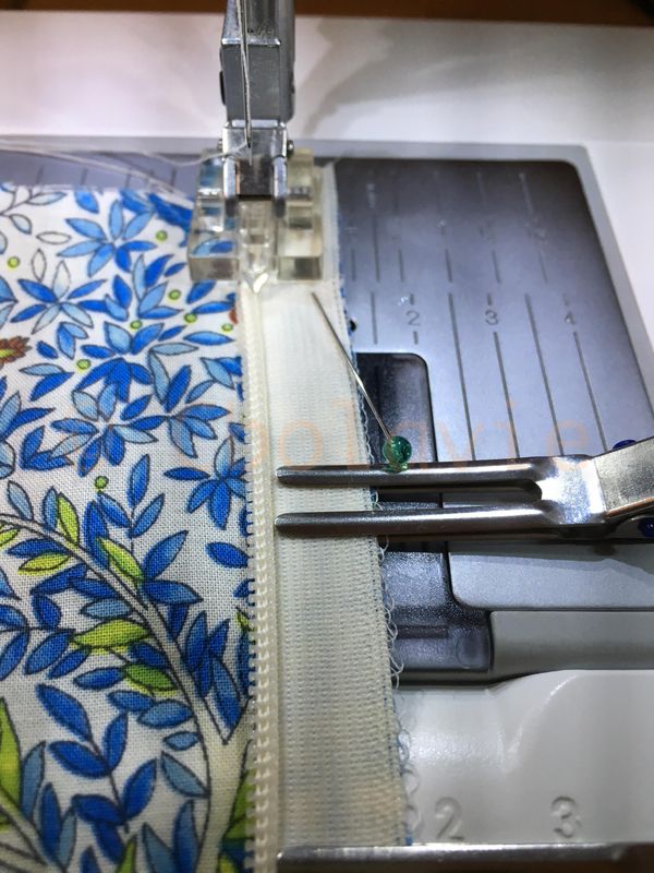 the sewing machine is stitching fabric with needle and thread on it's side